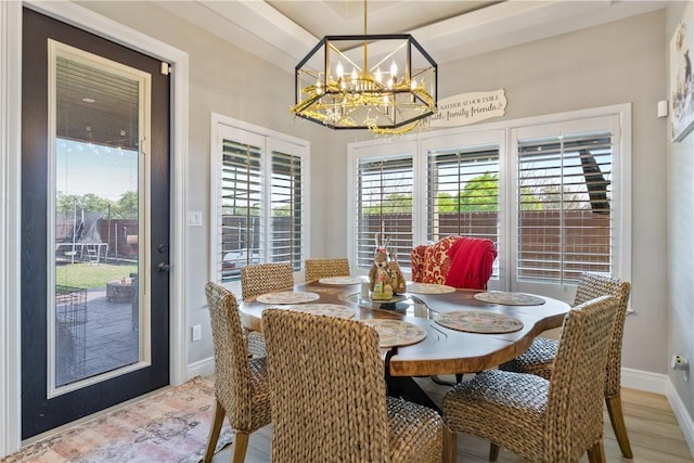 dining room featuring baseboards, wood finished floors, and an inviting chandelier