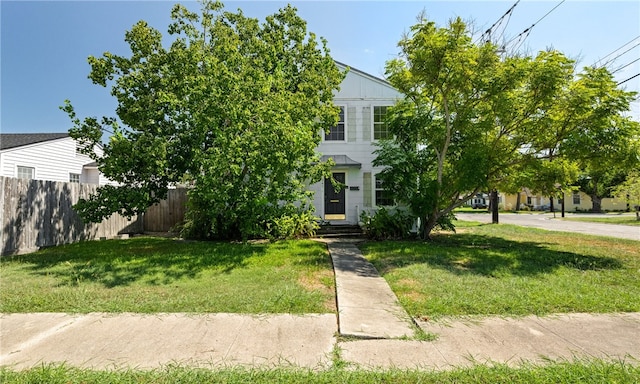 view of property hidden behind natural elements featuring a front yard