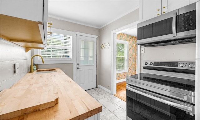 kitchen with appliances with stainless steel finishes, sink, crown molding, and white cabinets