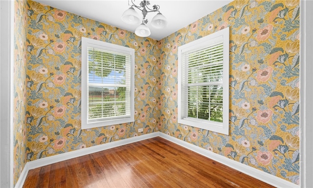 empty room featuring hardwood / wood-style floors, plenty of natural light, and an inviting chandelier