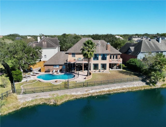 rear view of house featuring a lawn, a patio area, a balcony, and a water view