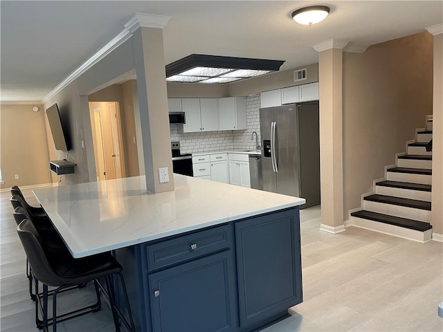 7029 Tamarron Ct, Corpus Christi, TX 78413 - kitchen with stainless steel appliances, a sink, light wood-type flooring, white cabinetry, and a kitchen bar