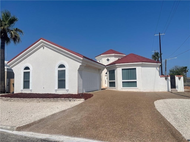 mediterranean / spanish house with a garage, driveway, and stucco siding