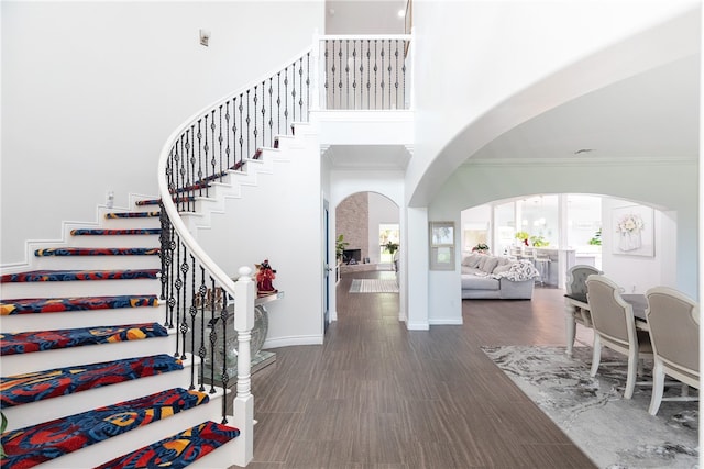 foyer entrance with ornamental molding, dark wood-type flooring, and a high ceiling