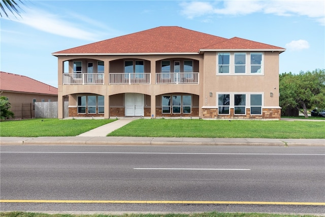 view of front of home featuring a front lawn and a balcony