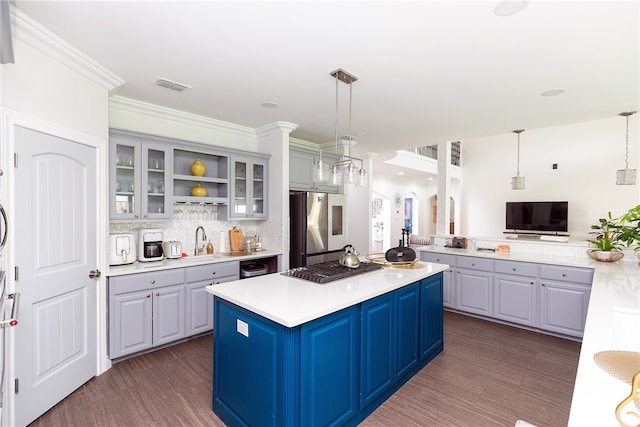 kitchen featuring hanging light fixtures, a kitchen island, stainless steel refrigerator, and blue cabinets