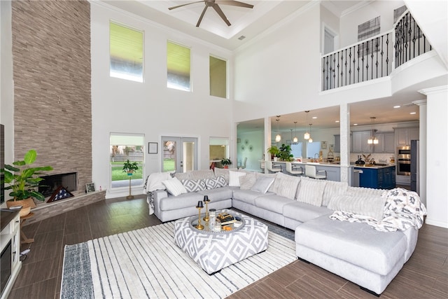 living room with a high ceiling, dark wood-type flooring, ceiling fan, and a fireplace