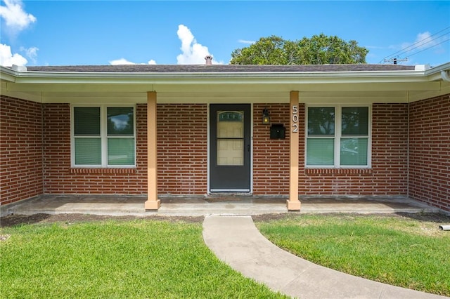 entrance to property with covered porch and a lawn