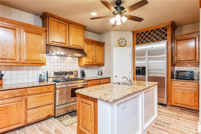 7601 Dijon Lake Dr, Corpus Christi, TX 78413 - kitchen with stainless steel appliances, under cabinet range hood, light wood-type flooring, ceiling fan, and tasteful backsplash