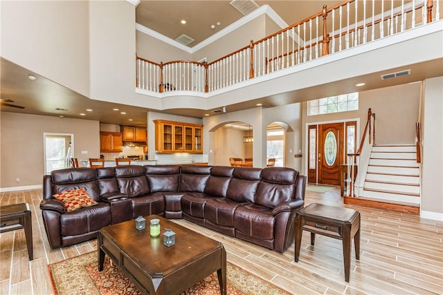 7601 Dijon Lake Dr, Corpus Christi, TX 78413 - living room featuring ornamental molding, arched walkways, light wood-style flooring, a high ceiling, and stairway