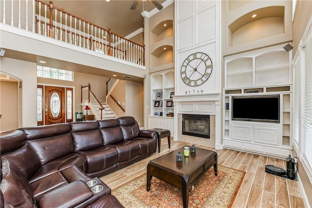 7601 Dijon Lake Dr, Corpus Christi, TX 78413 - living area featuring built in shelves, wood tiled floors, a towering ceiling, a tiled fireplace, and stairway