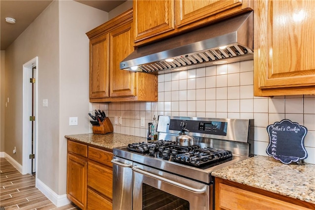 7601 Dijon Lake Dr, Corpus Christi, TX 78413 - kitchen featuring gas range, exhaust hood, backsplash, light stone countertops, and brown cabinets