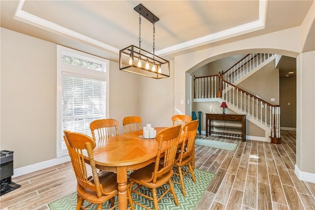 7601 Dijon Lake Dr, Corpus Christi, TX 78413 - dining room featuring a raised ceiling, light wood finished floors, arched walkways, stairs, and ornamental molding