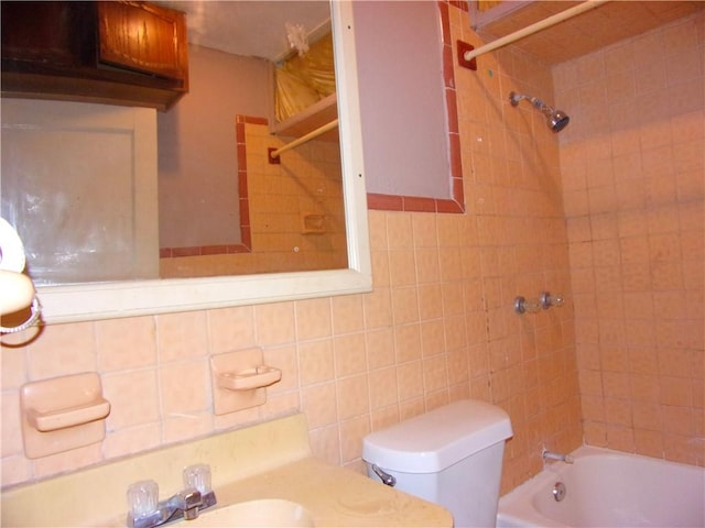 full bathroom featuring backsplash, sink, tiled shower / bath, toilet, and tile walls