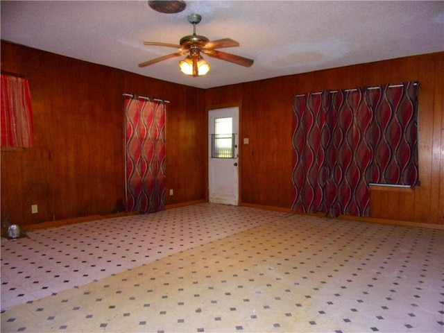 interior space featuring ceiling fan and wood walls