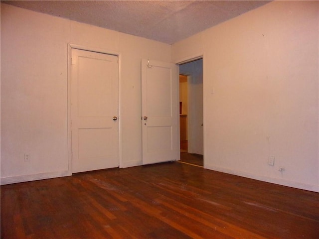 unfurnished bedroom featuring a textured ceiling and dark wood-type flooring