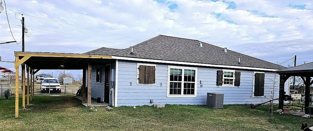 back of house featuring central air condition unit and a yard