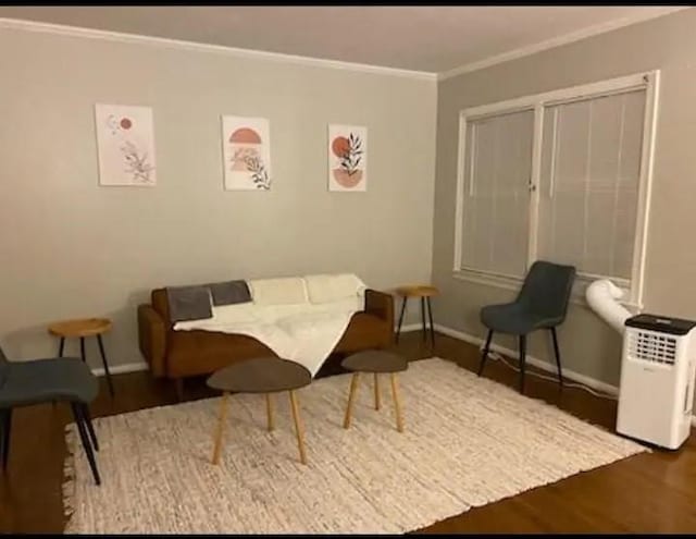 living area with crown molding and hardwood / wood-style flooring