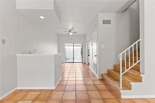 foyer entrance with ceiling fan and light tile patterned flooring