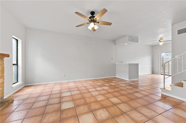 unfurnished living room with a healthy amount of sunlight, light tile patterned floors, a fireplace, and ceiling fan