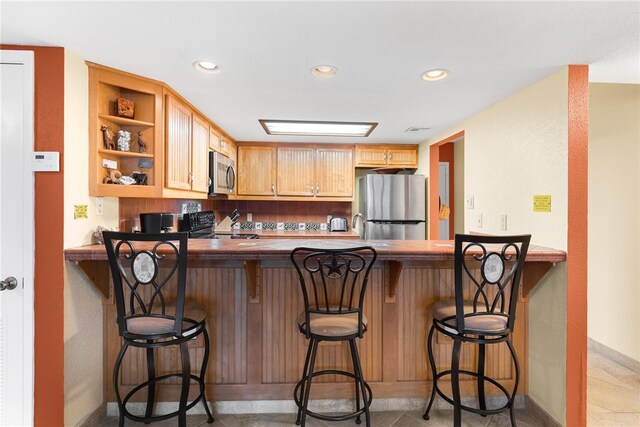 kitchen with appliances with stainless steel finishes, recessed lighting, a peninsula, and open shelves