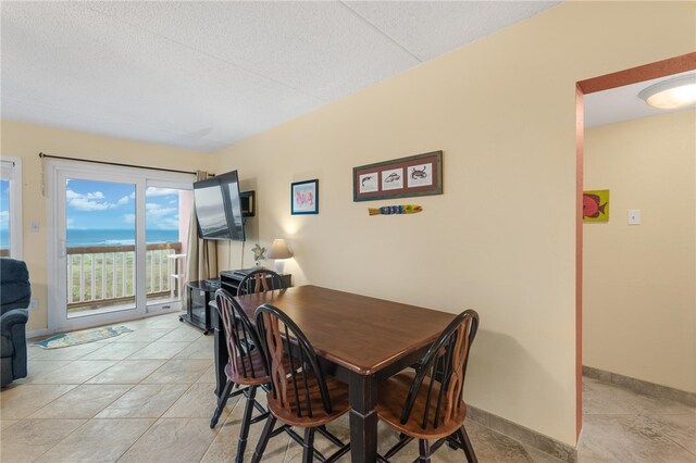 dining room featuring light tile patterned floors, baseboards, and a textured ceiling