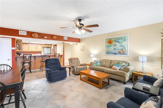 living area with a ceiling fan, visible vents, a textured ceiling, and light tile patterned flooring