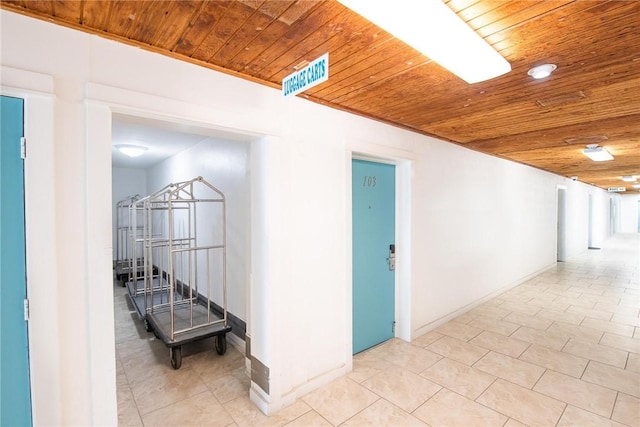 hall with tile patterned flooring, wooden ceiling, and baseboards