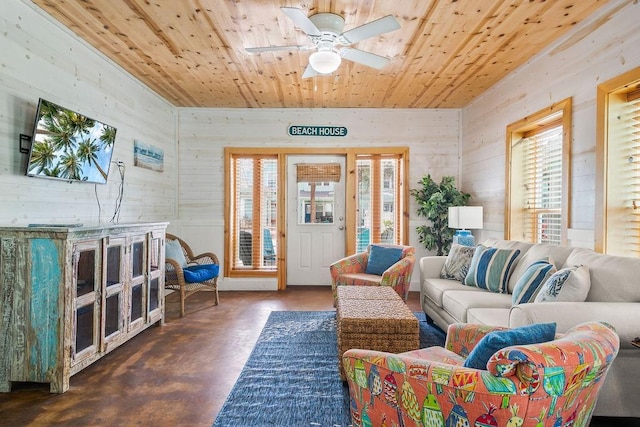 living room with ceiling fan, wooden ceiling, wood walls, and finished concrete floors