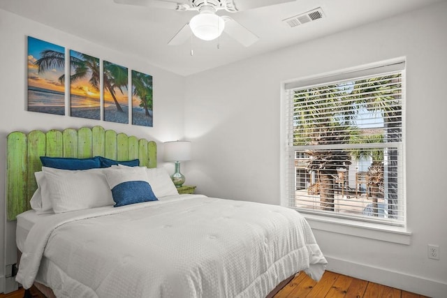 bedroom featuring visible vents, baseboards, wood finished floors, and a ceiling fan