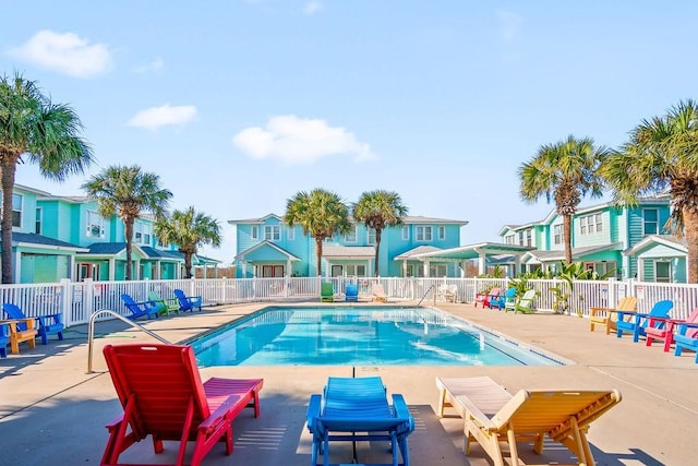 community pool with a patio area, a residential view, and fence