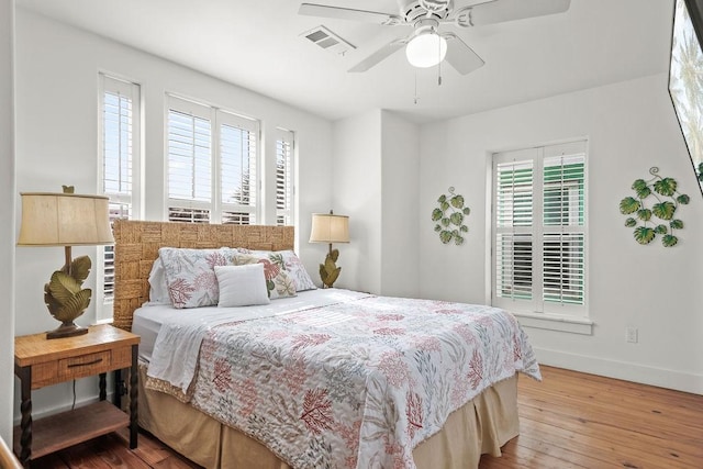 bedroom with visible vents, ceiling fan, baseboards, and hardwood / wood-style flooring