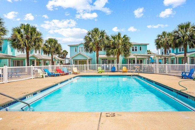 pool with a patio, fence, and a residential view