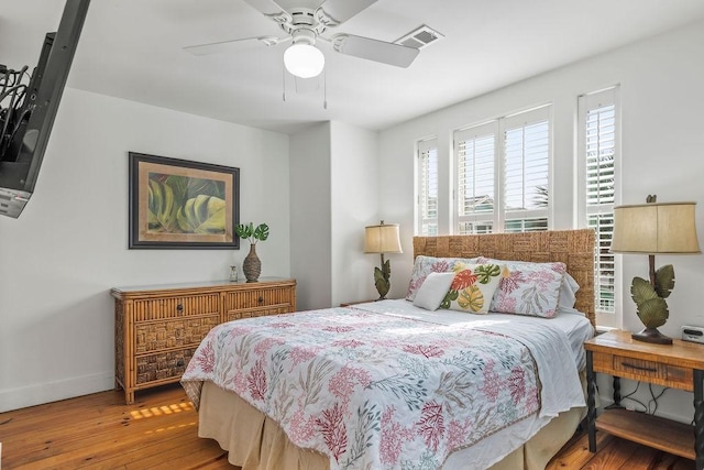 bedroom featuring visible vents, wood-type flooring, baseboards, and ceiling fan