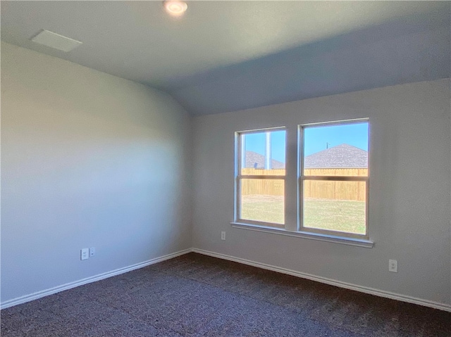 empty room featuring lofted ceiling and dark carpet