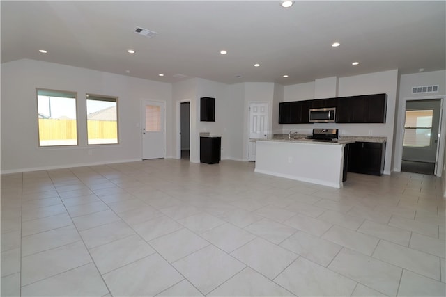 kitchen with an island with sink, black range, light tile patterned floors, and sink