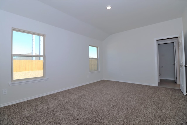 carpeted spare room featuring vaulted ceiling