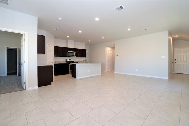 kitchen with stainless steel appliances, light tile patterned flooring, and an island with sink