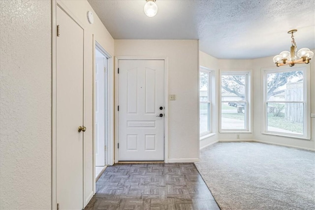 foyer entrance featuring a textured ceiling, baseboards, and an inviting chandelier