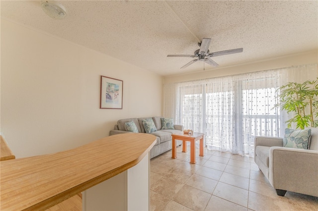 living room with ceiling fan, a textured ceiling, and light tile patterned floors