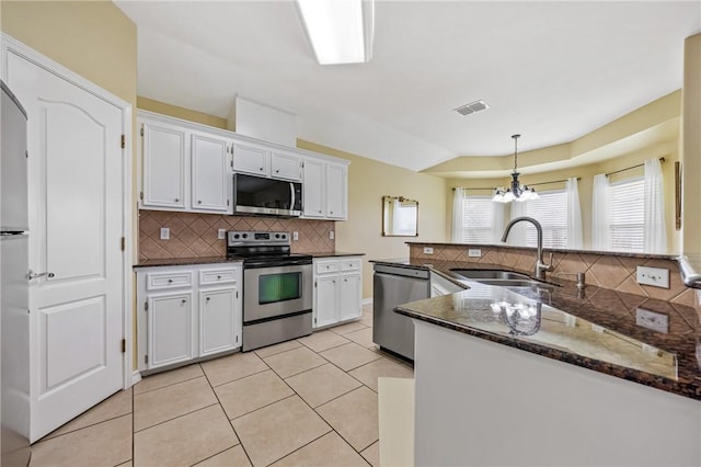 3137 Masterson Dr, Corpus Christi, TX 78415 - kitchen with appliances with stainless steel finishes, decorative backsplash, light tile patterned floors, a chandelier, and white cabinetry