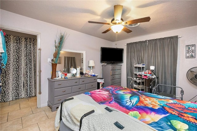 bedroom with a textured ceiling, ceiling fan, and light tile patterned floors