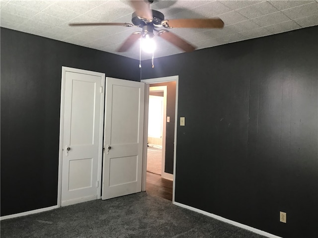 unfurnished bedroom featuring dark colored carpet and ceiling fan