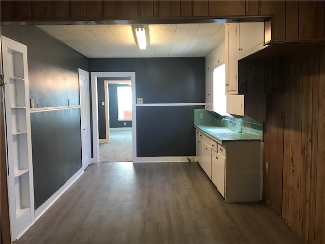 kitchen featuring white cabinetry, wooden walls, sink, and dark hardwood / wood-style floors