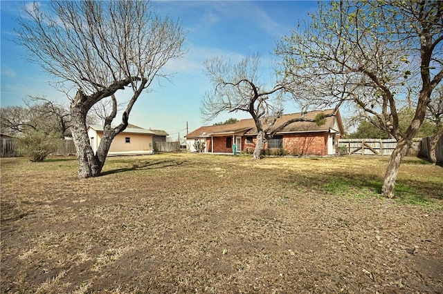 rear view of house with a yard, brick siding, and fence