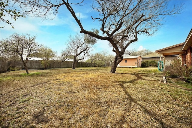 view of yard featuring a storage shed, a fenced backyard, and an outdoor structure