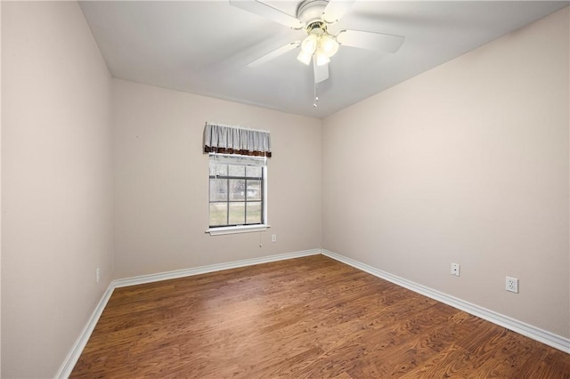 spare room with wood finished floors, a ceiling fan, and baseboards