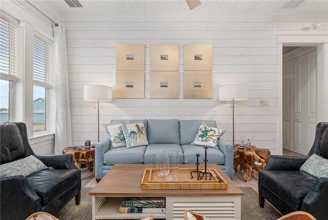 living room with hardwood / wood-style flooring, a healthy amount of sunlight, and wood walls