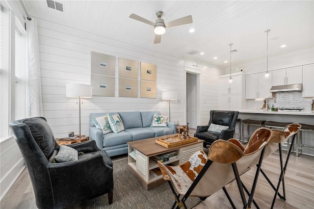 living room featuring light hardwood / wood-style floors, wooden ceiling, and ceiling fan