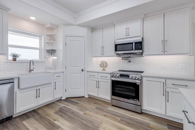 kitchen featuring sink, white cabinetry, crown molding, light wood-type flooring, and appliances with stainless steel finishes